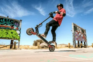Un jeune homme tente de démontrer une performance d'un moteur de trottinette électrique en effectuant une figure acrobatique sur roue arrière.