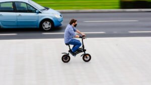 Un jeune homme s'élance rapidement avec sa draisienne électrique fraîchement réparée. Les pièces détachées draisienne électrique MOOVWAY jouent un rôle crucial dans la maintenance, la réparation et la personnalisation de votre petit véhicule urbain.