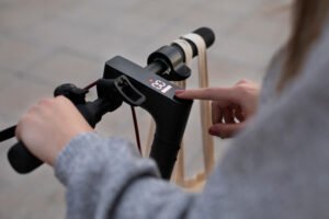 Une femme tente de réparer sa trottinette électrique en appuyant longuement sur le bouton.