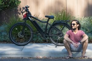 Un homme pose devant son magnifique vélo électrique sur le trottoir. Vélo électrique ou traditionnel, lequel est réellement fait pour lui ?