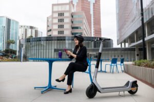 Une femme assise dehors est aller au travail en trottinette électrique