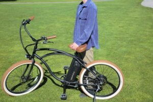 Un homme qui se demande comment entretenir son vélo électrique se tient debout sur la pelouse