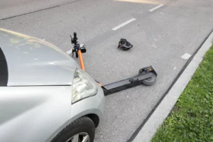 Une trottinette cassée reste au sol après un choc avec une voiture.
