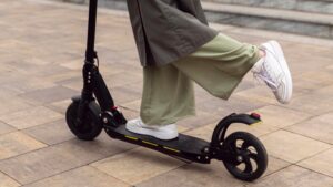 Une femme se tient sur sa trott équipée de la nouvelle norme chinoise sur les batteries de trottinettes électriques.